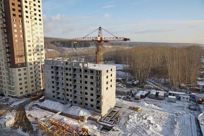 Construction site with crane and under construction high-rise apartment house.