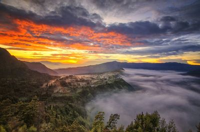 View of waterfall against cloudy sky during sunset