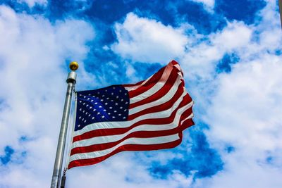 Low angle view of american flag waving against cloudy sky