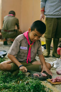 Boy cutting meat at outdoors