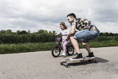 Boys riding bicycle on road against sky