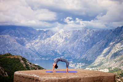 Woman with umbrella on mountain against sky