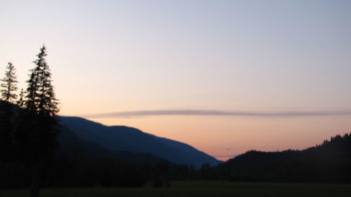 Scenic view of silhouette field against sky at sunset