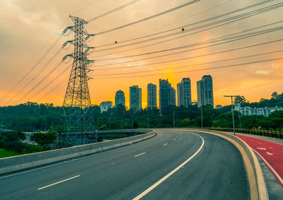 Road by city against sky during sunset