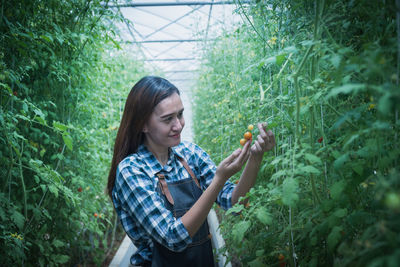 Young woman smiling while standing against plants