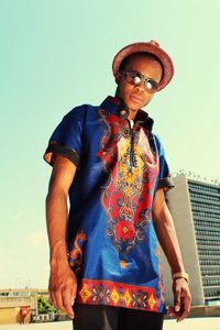 Portrait of young man standing in city against sky