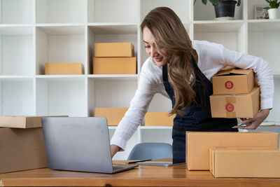 Side view of woman using laptop at home
