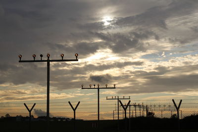 Low angle view of airport lights against sky during sunset