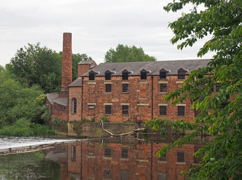 Buildings by river against sky