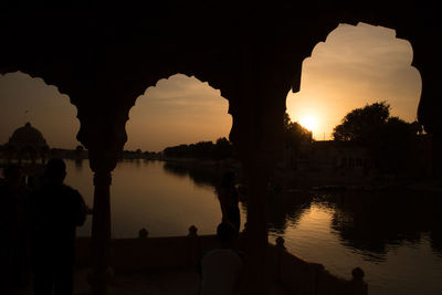 Silhouette bridge over lake against sky during sunset