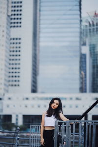 Portrait of woman standing against modern buildings in city