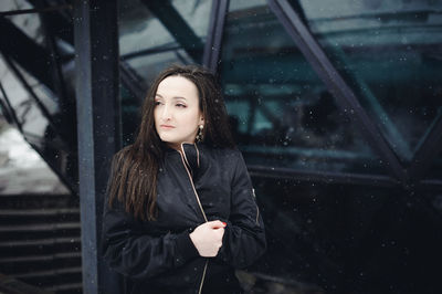 Young woman looking away while standing outdoors