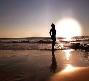 Silhouette man standing on beach against sky during sunset