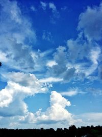 Low angle view of silhouette trees against blue sky