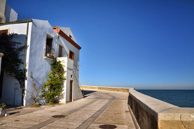 Building by sea against clear blue sky