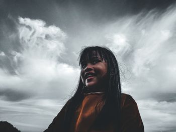 Portrait of beautiful young woman against sky