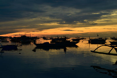 Silhouette boats in marina at sunset