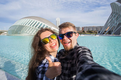 Portrait of smiling young woman wearing sunglasses against sea