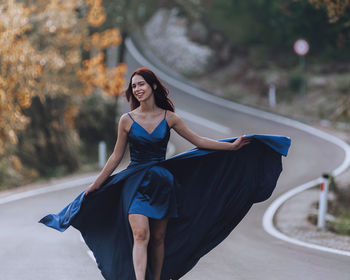 Portrait of young woman standing against trees