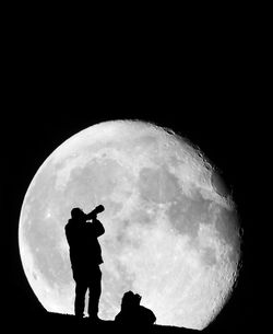 Silhouette man standing against moon at night