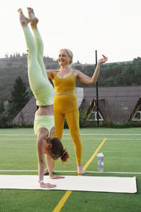 Full length of young woman exercising on field