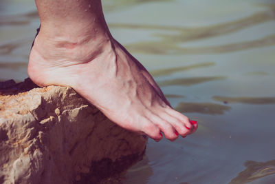 Low section of woman leg on rock over water