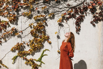 Woman standing by tree during autumn