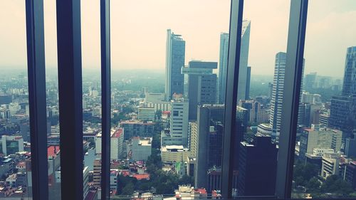 Cityscape against sky seen through glass window