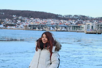 Portrait of smiling woman wearing warm clothing while standing in city