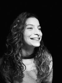 Portrait of a smiling young woman over black background