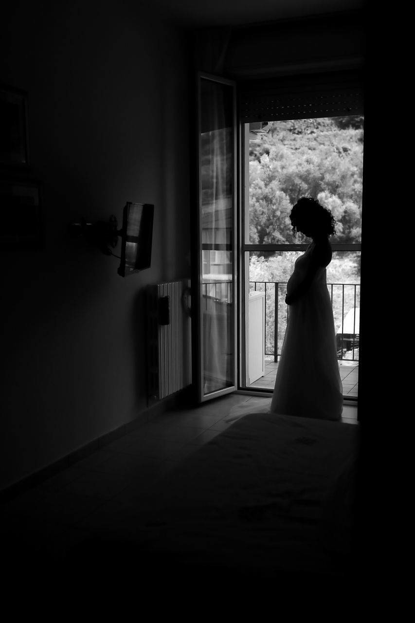 SIDE VIEW OF WOMAN LOOKING AT WINDOW