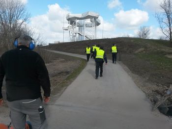 Rear view of people walking on road against sky