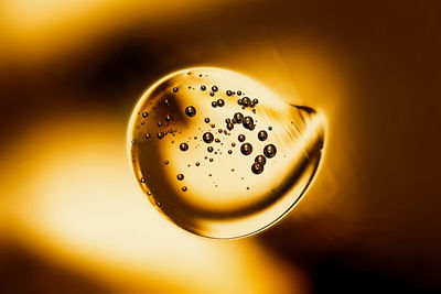 Transparent golden round smear of cosmetic serum with bubbles close-up
