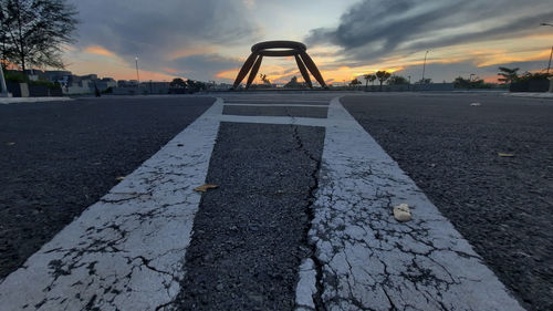 Surface level of road against sky at sunset