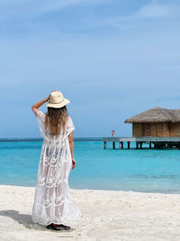Rear view of woman standing at beach in maldives