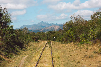 View of railroad tracks by mountain against sky