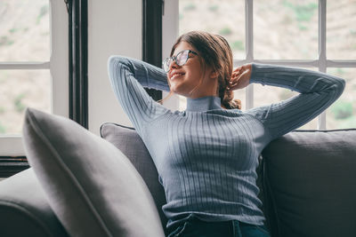 Young woman sitting on sofa at home