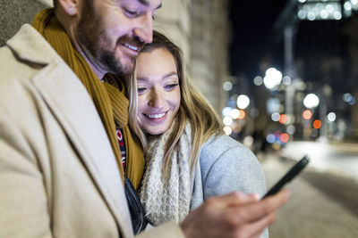 Happy young woman with man using smart phone