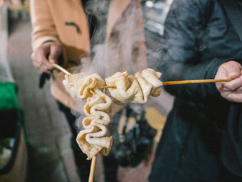 Close-up of people holding food with skewers