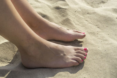 Low section of woman on sand at beach