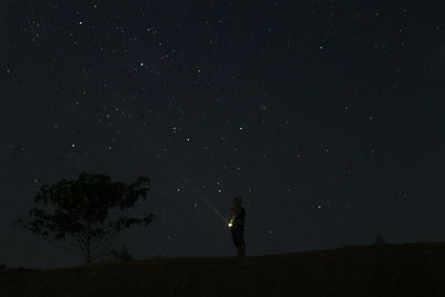 Silhouette person standing on field against sky at night