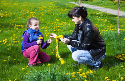 Mother and daughter holding yellow flowers on field