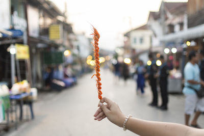 Woman holding ice cream cone on street in city