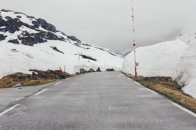 Road by snow covered mountain against sky