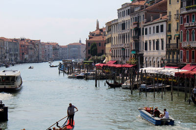 People in boat sailing on river against sky in venice