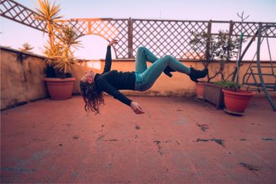 Full length of young woman jumping outdoors