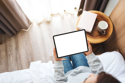 Midsection of woman using digital tablet at home