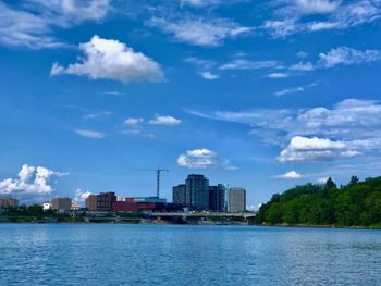 Buildings by sea against blue sky