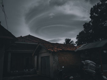 House amidst trees and buildings against sky