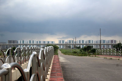 Empty seats on footpath in city against sky